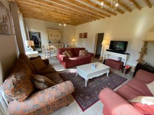 Stunning 5 bedroom French Manor house, Normandy في Beaunay: غرفة معيشة بها كنب احمر وطاولة بيضاء