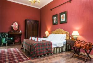 1 dormitorio con paredes rojas, 1 cama y 1 silla en Lancaster Court Hotel, en San Petersburgo
