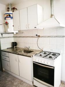 een witte keuken met een fornuis en een wastafel bij Casa check in Dpto 2 a 4 pers in Neuquén