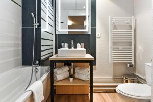 La salle de bains est pourvue d'un lavabo, d'une baignoire et de toilettes. dans l'établissement Appart'City Confort Lille - Euralille, à Lille