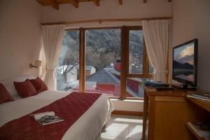 a bedroom with a bed and a large window at Hotel Antiguos in San Martín de los Andes