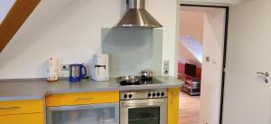 a kitchen with yellow cabinets and a stove top oven at Ferienwohnung am Hollergraben in Oberschwarzach