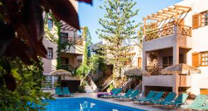 a resort pool with chairs and umbrellas at Anna Maria in Malia