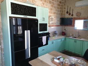a kitchen with green cabinets and a black refrigerator at Jasmine House in Acre