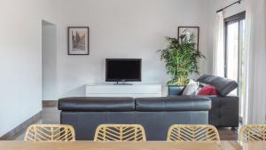 a living room with a black leather couch and a tv at Pool House Marineta in Es Llombards