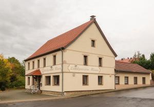 a large white building with a red roof at Landpension Minna in Herbsleben