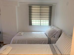 a white bedroom with a bed and a window at Alquiler temporario Mendoza in Mendoza
