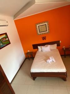 a bedroom with a bed with an orange wall at Hotel Doña Marta in Nicoya +5 photos