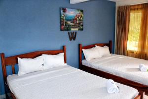 2 camas en una habitación con paredes azules en Hotel Doña Marta, en Nicoya