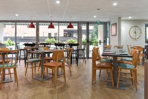 a dining room with tables and chairs and windows at Appart'City Confort Lille - Euralille in Lille