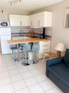 a kitchen with white cabinets and a table and a couch at T3 VUE ETANG in Balaruc-les-Bains
