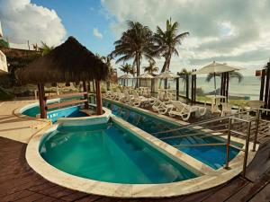 a pool at a resort with tables and chairs at Elegance Suítes Beira Mar in Natal