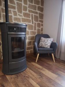 a living room with a fireplace and a chair at Casa rural fuentelgato in Huerta del Marquesado