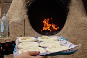 a person holding a tray of uncooked dough in front of an oven at Barskoon Guest House in Barskoon