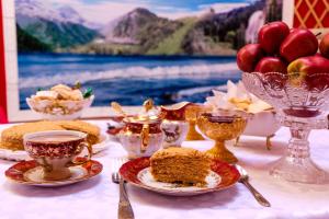 a table with cups and plates of food and fruit at Barskoon Guest House in Barskoon