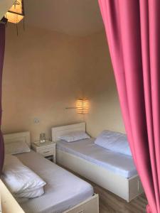 2 Betten in einem Zimmer mit rosa Vorhängen in der Unterkunft Mone's Mountain View Hotel in Kāskī