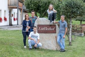 un groupe de personnes debout à côté d'un panneau dans l'établissement Loefflerhof, à Monguelfo-Tesid