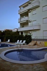 una piscina con sillas y un edificio en Apartments Paradise, en Trogir