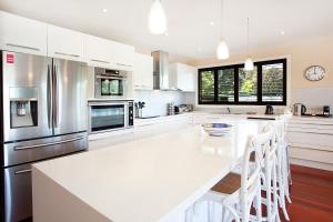 a white kitchen with a large white table and appliances at Spacious Family Entertainer for Manly Retreat DUPLICATE in Sydney