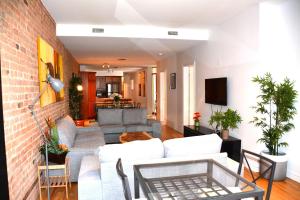 a living room with a white couch and a brick wall at Le Metro Mont-Royal by HomeInMontreal in Montreal