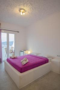 1 dormitorio blanco con 1 cama grande con sábanas moradas en George & Irene Hotel, en Ios Chora