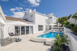 a villa with a swimming pool and a house at The Little Palm in Bloubergstrand