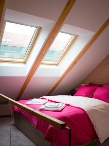 een slaapkamer met een bed met roze lakens en 2 ramen bij My Studio - La Magazie in Braşov