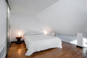 - une chambre avec un lit blanc et un mur en verre dans l'établissement Oktheway Loft Maestranza, à La Corogne