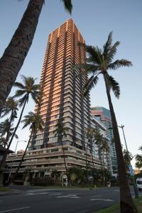 檀香山的住宿－Waikiki Monarch Hotel，一条街道前方有棕榈树的高楼