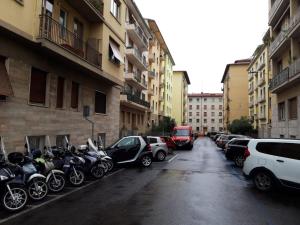 Une rangée de motos et de voitures garées dans un parking dans l'établissement Fiorino House, à Florence