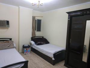 a small bedroom with two beds and a black cabinet at El Ahram Hostel & Apartments in Cairo