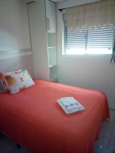 a bedroom with a bed with a red blanket and a window at Aptos Farroupilha in Farroupilha