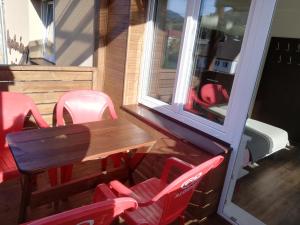 une table en bois et des chaises rouges sur la terrasse dans l'établissement Apartmany Agatha, à Loučná nad Desnou