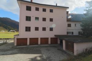 a large white building with brown doors and a garage at Golf Apartments - Schmid in Davos