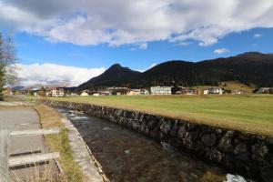 a stone wall next to a field and a river at Golf Apartments - Schmid in Davos