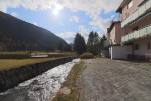 a river next to a building and a mountain at Golf Apartments - Schmid in Davos