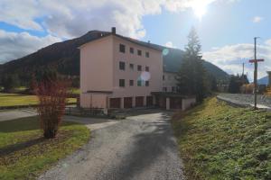a building on a road next to a mountain at Golf Apartments - Schmid in Davos