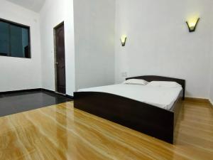 a bedroom with a bed and a wooden floor at Shobha Farmhouse in Kashid
