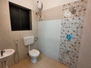 a bathroom with a toilet and a shower and a sink at Shobha Farmhouse in Kashid