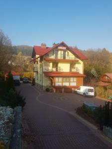 a house with a car parked in front of it at Noclegi Pod Orlikiem CENTRUM in Ustrzyki Dolne
