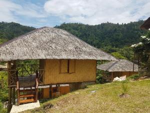 een kleine hut met een rieten dak op een heuvel bij Backpacker's Hill Resort in San Vicente