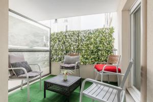 uma varanda com cadeiras e mesas e uma sebe verde em Appartement spacieux avec terrasse près de Paris et du Stade de France em Saint-Denis