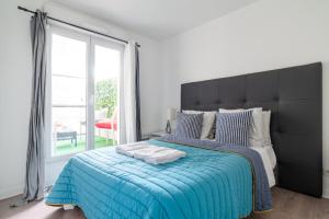 a bedroom with a large bed with a blue blanket at Appartement spacieux avec terrasse près de Paris et du Stade de France in Saint-Denis