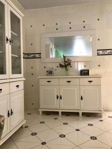 uma cozinha com armários brancos e um espelho em Casa de Sufia em Alto Paraíso de Goiás