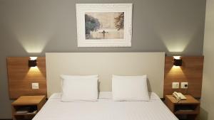 a bed with two pillows and a picture on the wall at Hotel Central Parque in São Lourenço