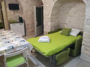 a room with a green bed in a stone wall at Trulli Manuela 2 in Locorotondo