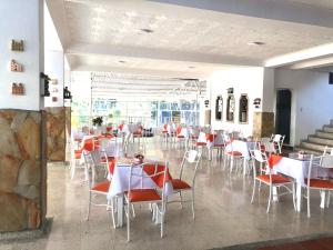 un comedor con mesas blancas y sillas rojas en HOTEL GIRON CAMPESTRE, en Girón