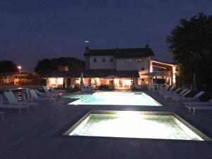 una piscina por la noche con sillas y un edificio en B&B La Corte Dei Vizi en Clauiano