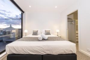 メルボルンにあるQ Squared Serviced Apartmentsの大きなベッドと大きな窓のある寝室
