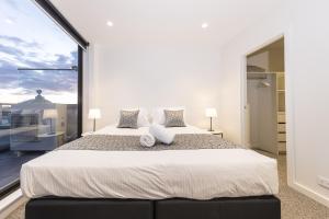 a bedroom with a large bed and a large window at Q Squared Serviced Apartments in Melbourne